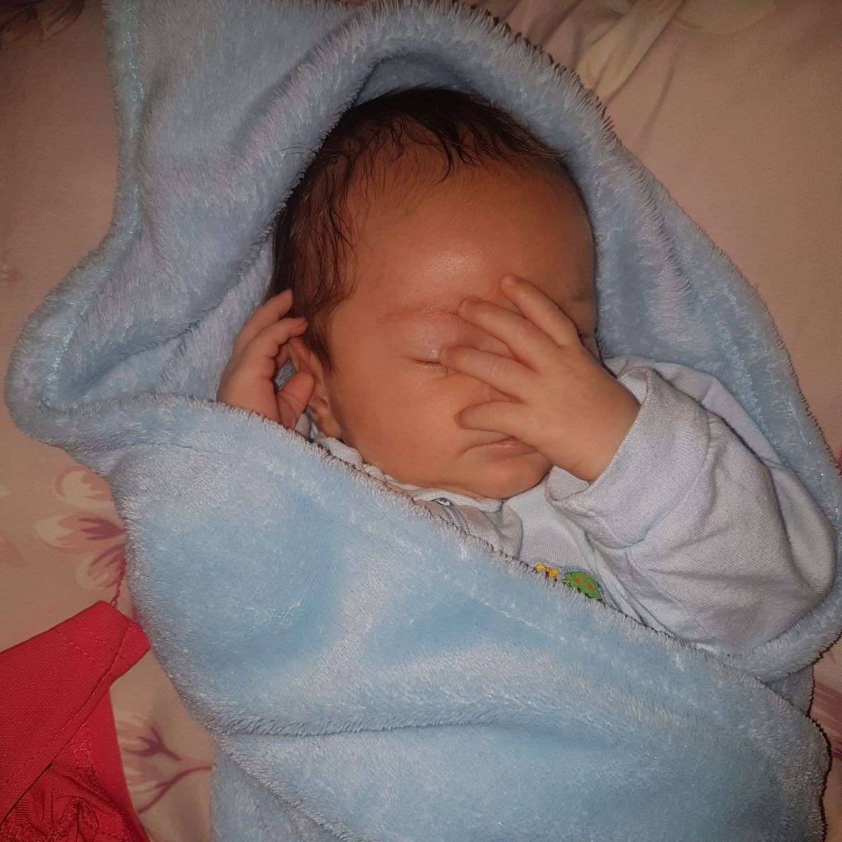 baby covering face with hand
