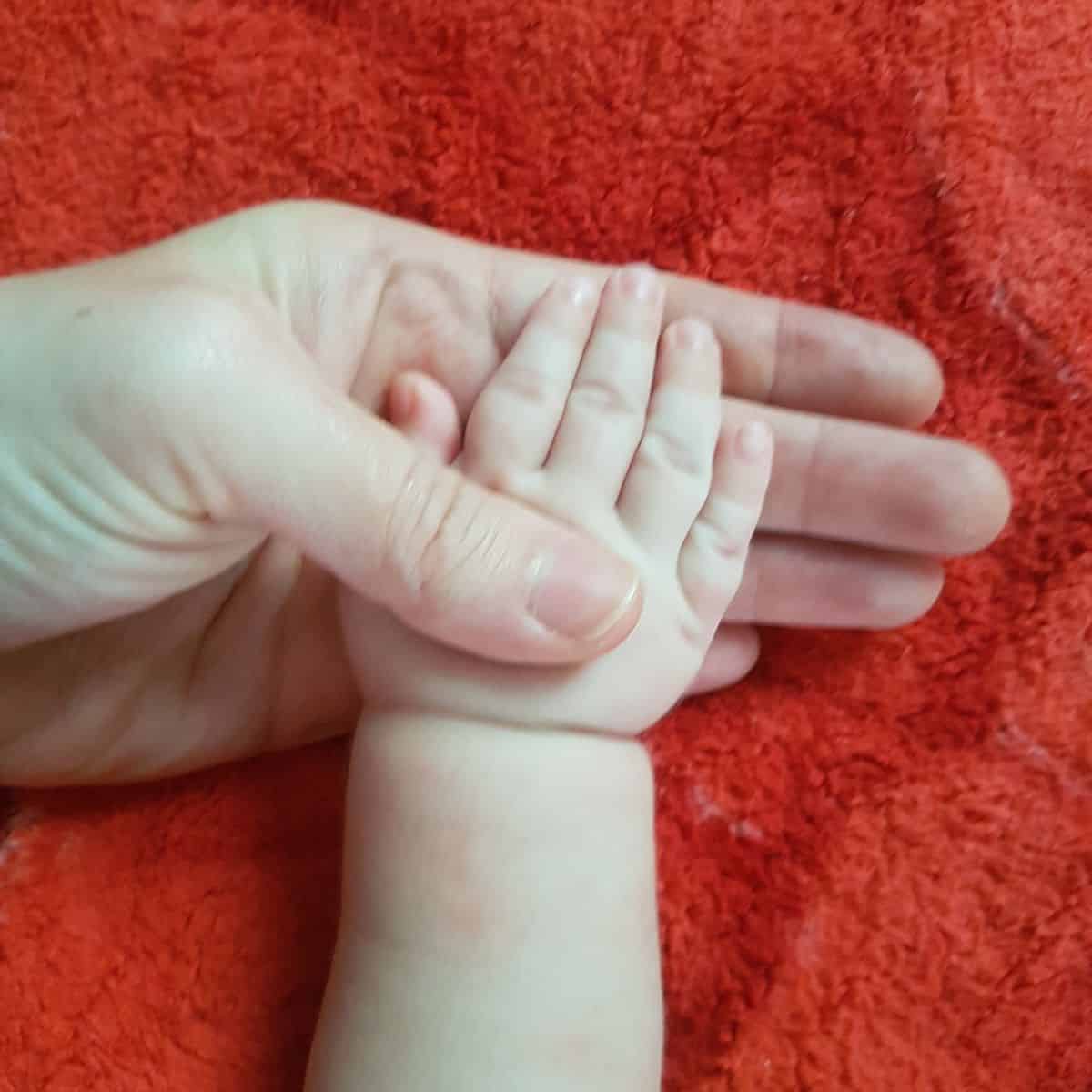 mom's hand holding baby's hand