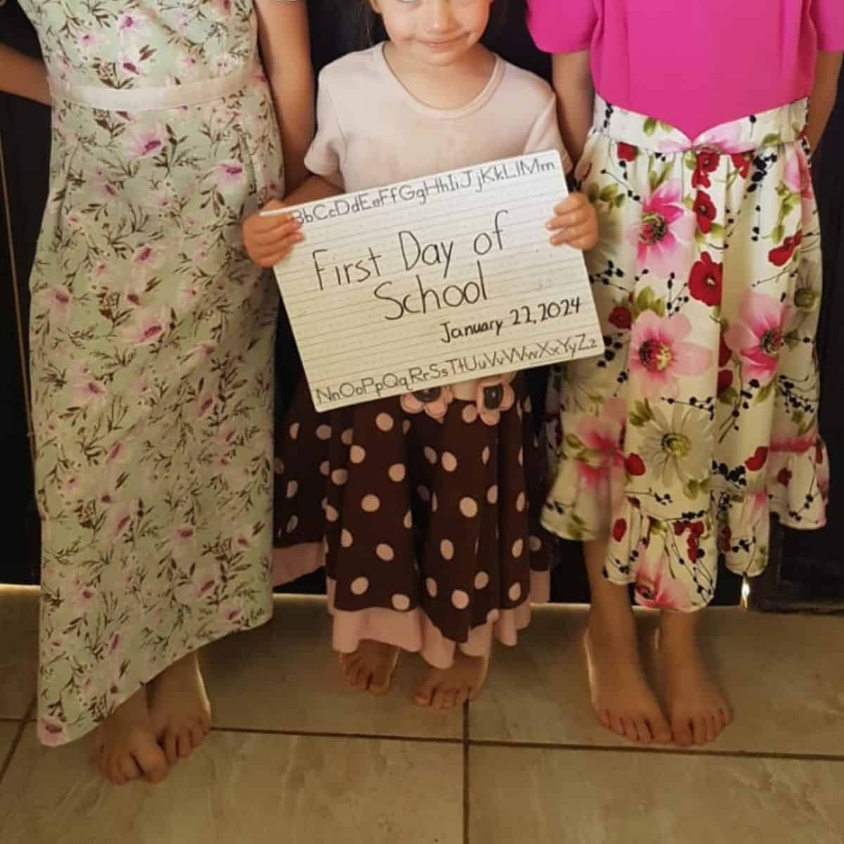 girls holding first day of school signs