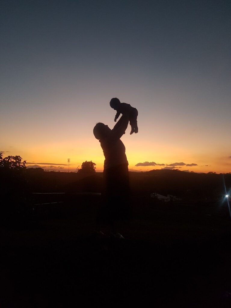 silhouete of mother holding up her baby.